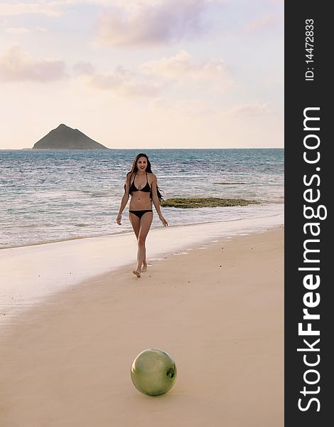 Young woman discovers a glass float net ball on a hawaii beach