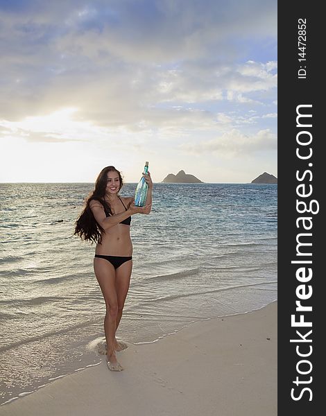 Young woman on the beach finds a bottle with a note in it