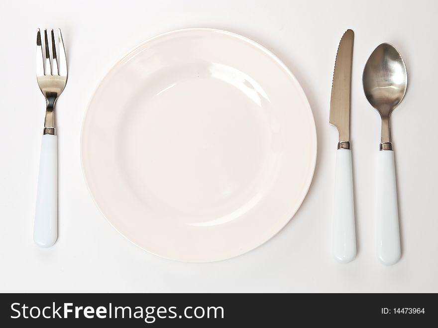 Set of kitchen object. The spoon, fork and knife with plate on a grey background. Set of kitchen object. The spoon, fork and knife with plate on a grey background.