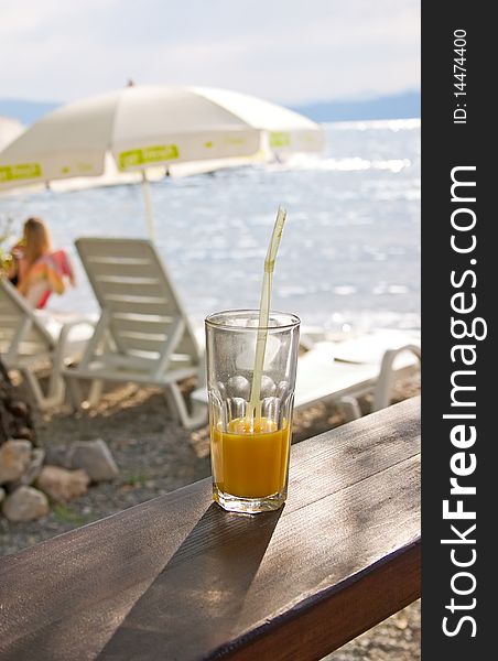 Beach scene with juice, easy chair and parasol