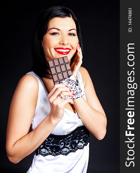 Pretty happy young brunette woman eating dark chocolate. Pretty happy young brunette woman eating dark chocolate