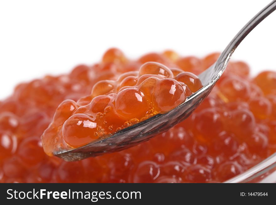 Red caviar in the little glass bow and spoon fragment isolated over white background