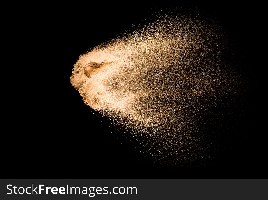 Sand explosion isolated on black background. Freeze motion of sandy dust splashing.