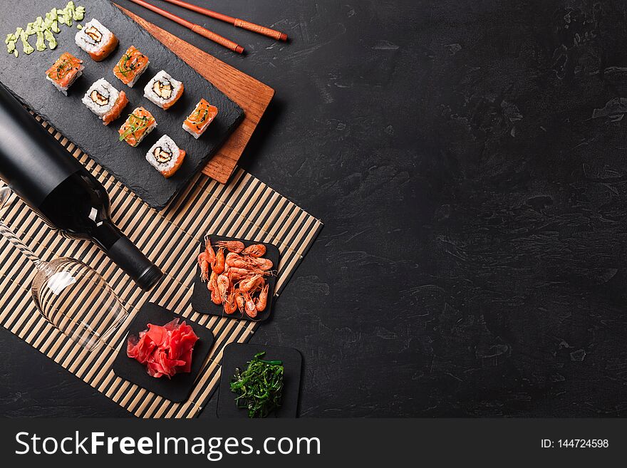 Set of sushi and maki with a bottle of wine on stone table. Top view with copy space