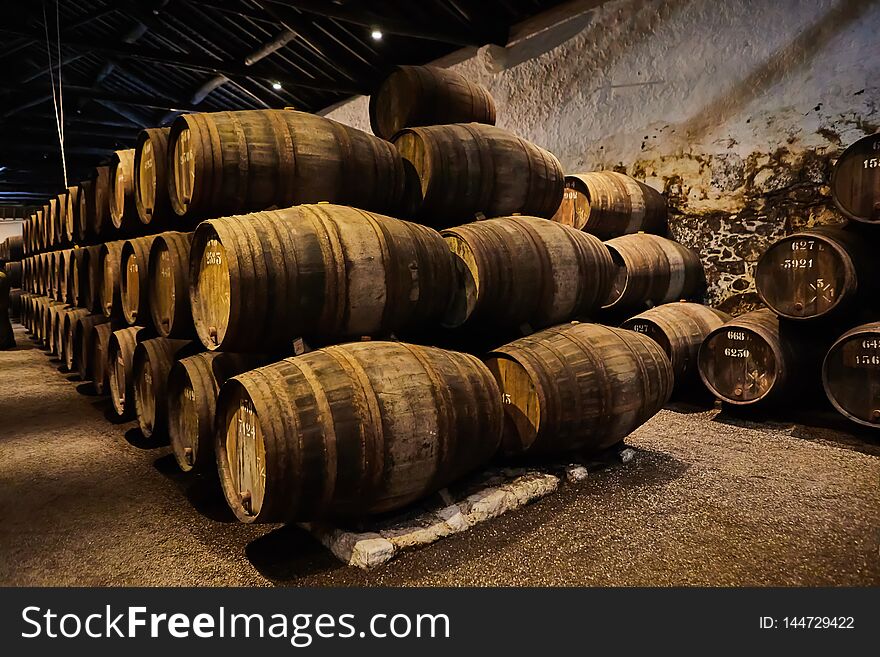 Old aged traditional wooden barrels with wine in a vault lined up in cool and dark cellar in Italy, Porto, Portugal, France