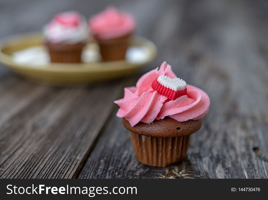 Pink and white muffins on wooden ground with heart whipping cream. Pink and white muffins on wooden ground with heart whipping cream