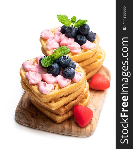 Stack  of heart shaped waffles with pink cream and blueberry isolatedon white