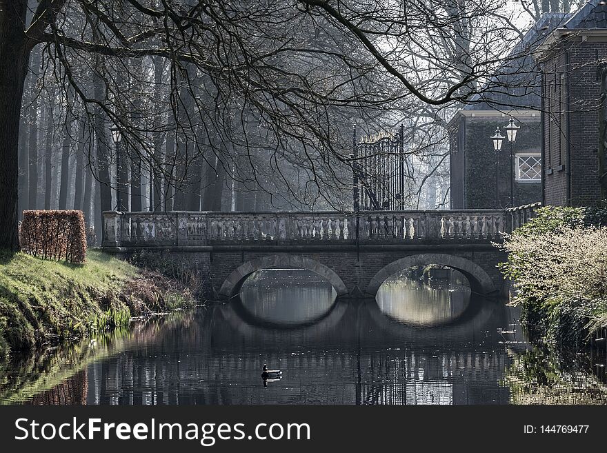 Mysterious bridge reflected in water on a foggy morning  in Laren, Netherlands