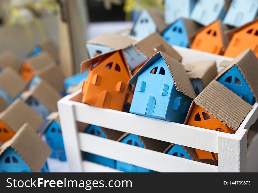 Paper houses in different colors, orange, blue, cyan inside wooden frame