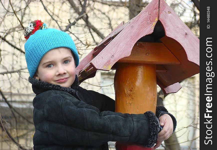 A little boy in warm clothing climbed on the playground on a wooden pole adorned. A little boy in warm clothing climbed on the playground on a wooden pole adorned