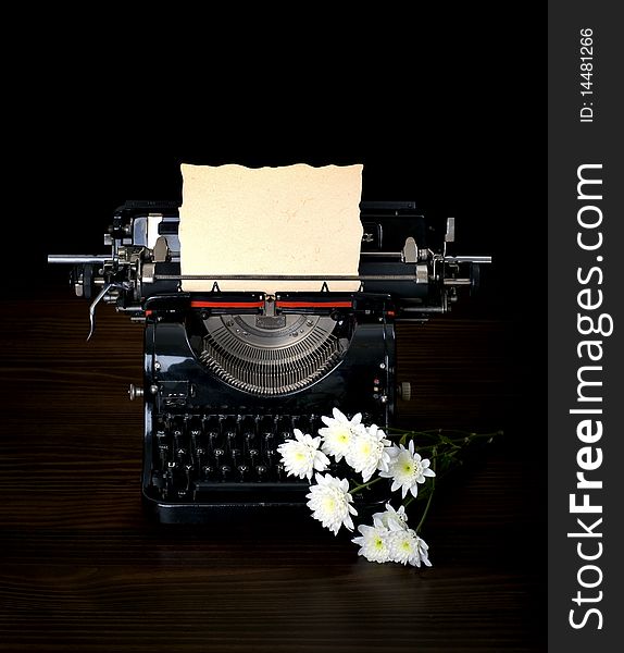 Antique typing machine with paper for text and flowers on dark background. Antique typing machine with paper for text and flowers on dark background