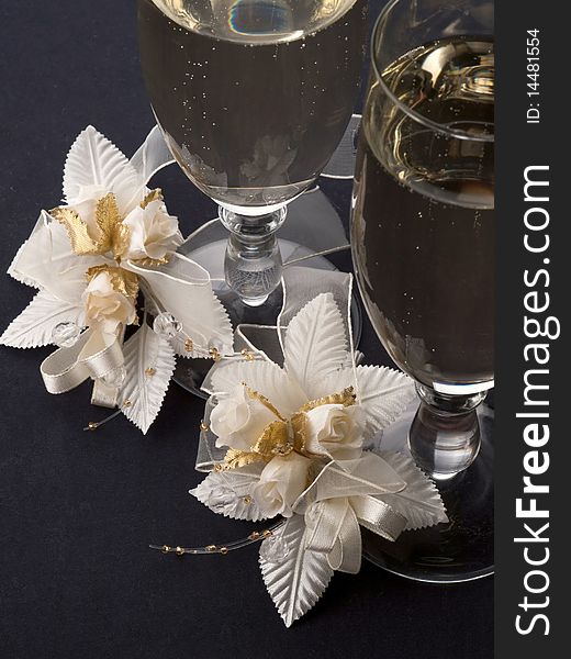 Glasses with champagne and weddings buttonholes  on a dark background