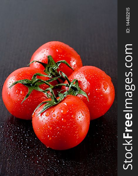 Fresh ripe tomatoes with drops of water isolated on wooden table. Fresh ripe tomatoes with drops of water isolated on wooden table