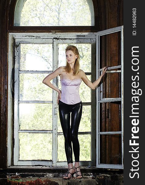 Fashion model is posing in front of the windows in abandoned house.