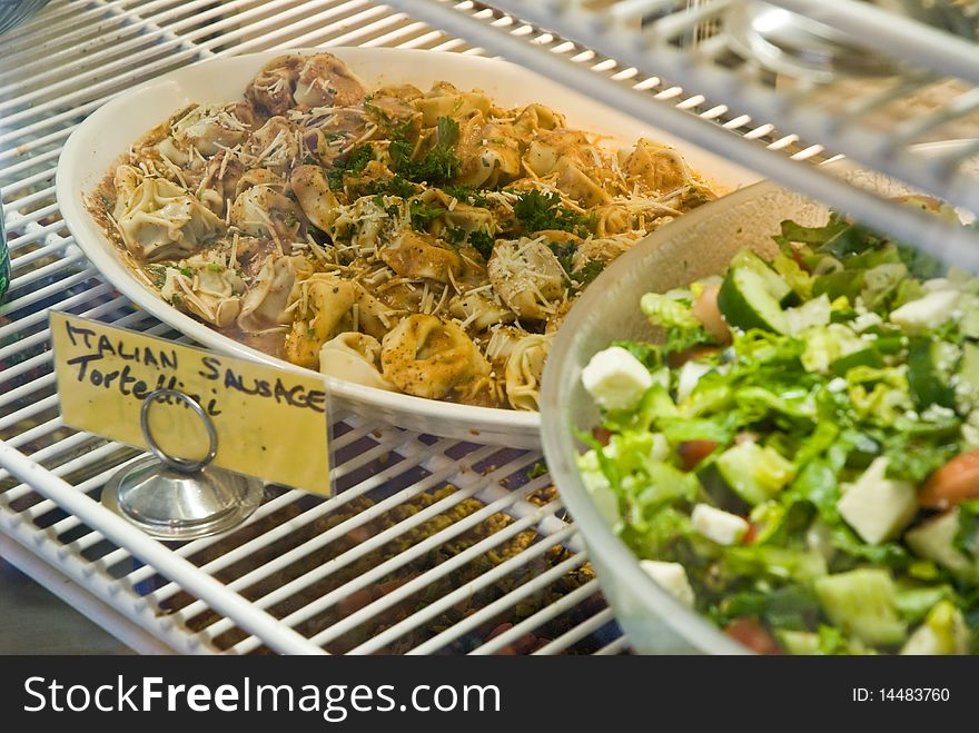 Ilalian Sausage tortellini and greek salad in a display case. Ilalian Sausage tortellini and greek salad in a display case