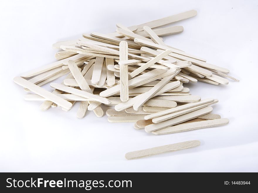 A bunch of wooden icecream sticks lying unarranged on a white surface