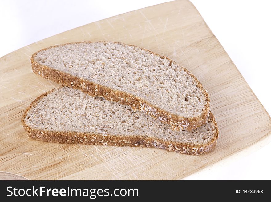 Two slices of brown bread lying on a wood board isolated on a white background