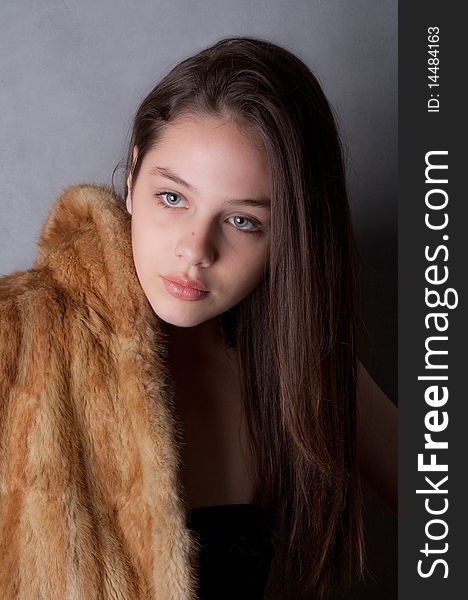 A portrait of a teenage model's face as she poses in a fur coat. A portrait of a teenage model's face as she poses in a fur coat