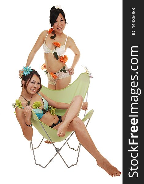 Two pretty Asian girls in lingerie, one sitting in a chair, the other one standing behind, with flowers around there bodies for white background. Two pretty Asian girls in lingerie, one sitting in a chair, the other one standing behind, with flowers around there bodies for white background.