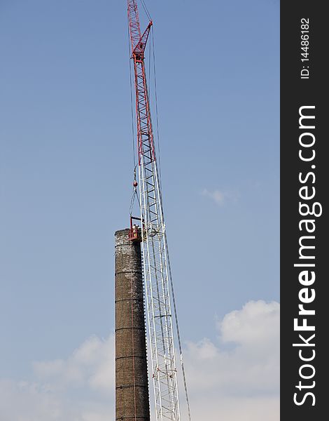 Men on large crane demolishing old smoke stack. Men on large crane demolishing old smoke stack