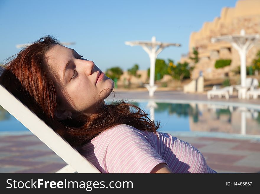 Young  woman relaxing in deck chair at resort hotel. Young  woman relaxing in deck chair at resort hotel