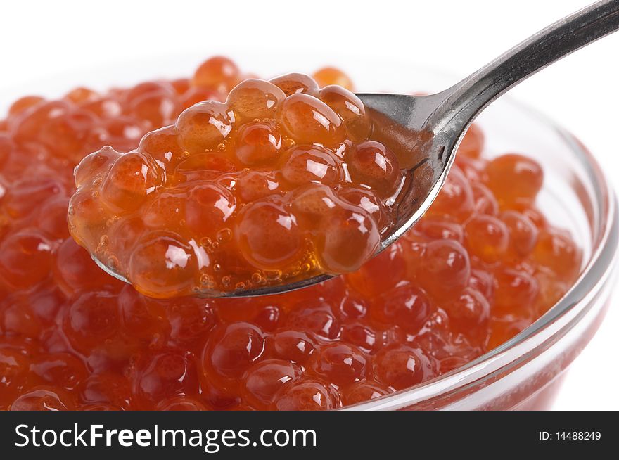 Red caviar in the little glass bow and spoon fragment isolated over white background