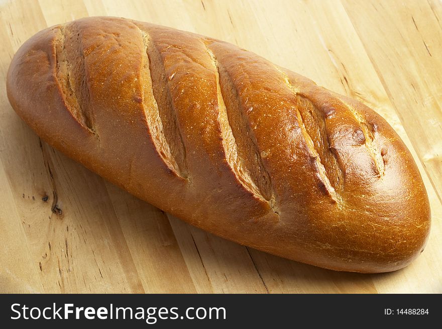 Shiny whole long bread over wooden desk background