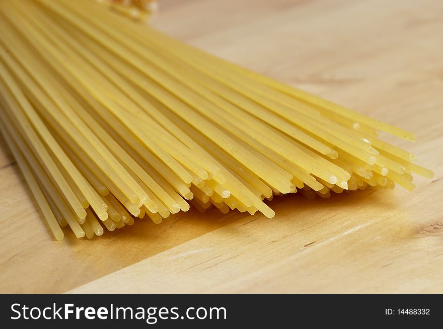 Wisp of raw spaghetti over wooden desk macro shot