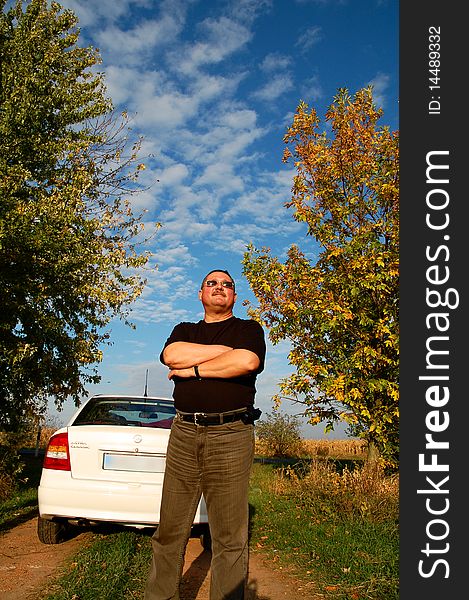 Proud man standing near his new car in a meadow. Proud man standing near his new car in a meadow.