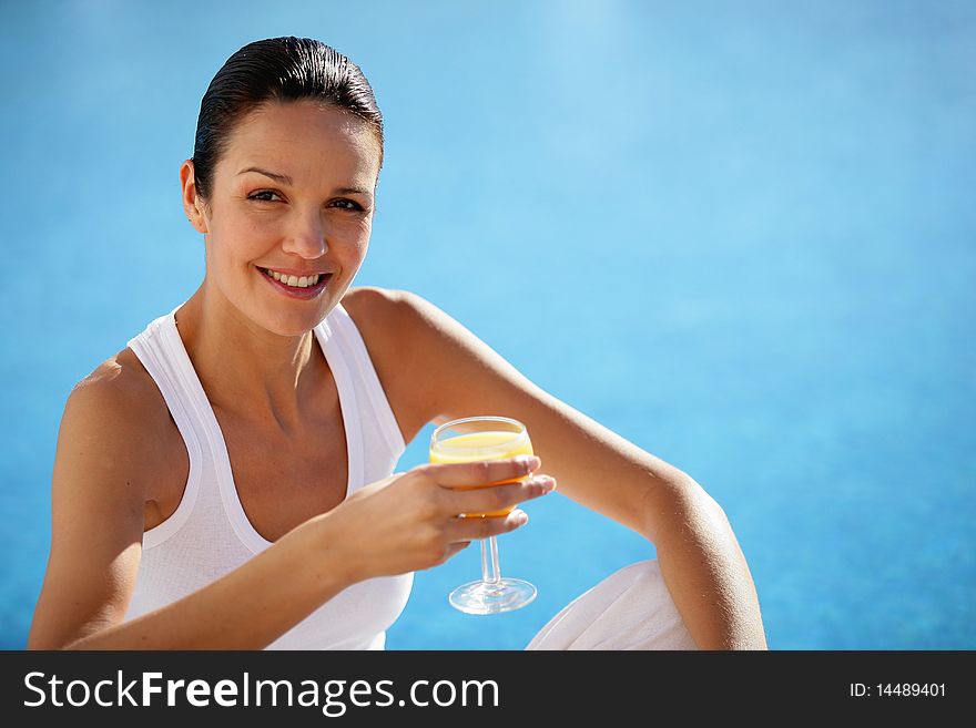 Portrait of woman holding glass of water by a pool. Portrait of woman holding glass of water by a pool
