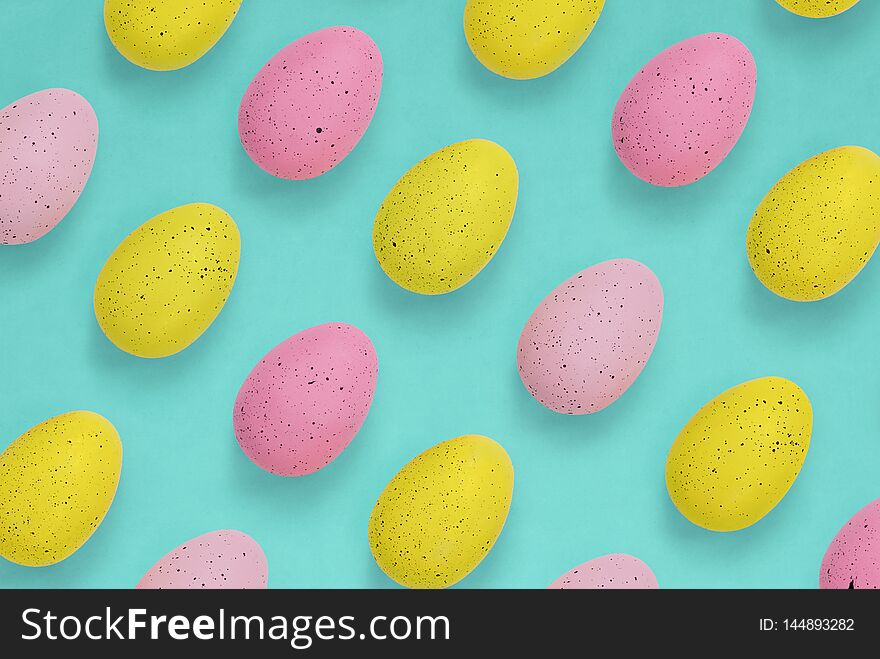Pink and yellow Easter eggs in a repeat pattern on a bright blue-green background. Pink and yellow Easter eggs in a repeat pattern on a bright blue-green background