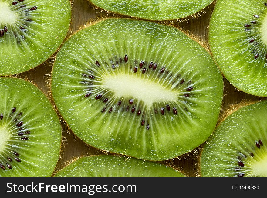 Sliced kiwi over wooden desk macro shot background. Sliced kiwi over wooden desk macro shot background