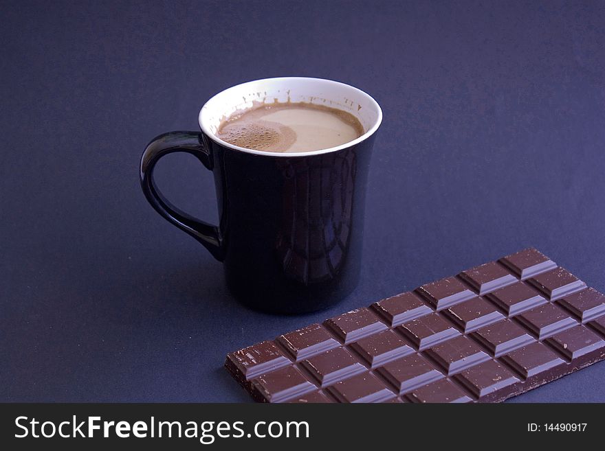 Coffee with milk in a black cup  with chocolate on a black background. Coffee with milk in a black cup  with chocolate on a black background.