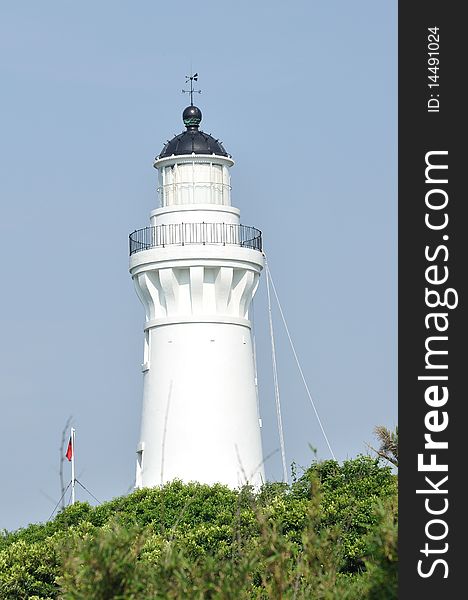 It is a white lighthouse with a flag
