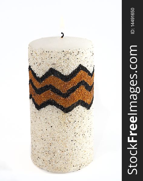 White candle, covered in tiny broken shells, with brown and black pattern, on a white bakcground. White candle, covered in tiny broken shells, with brown and black pattern, on a white bakcground