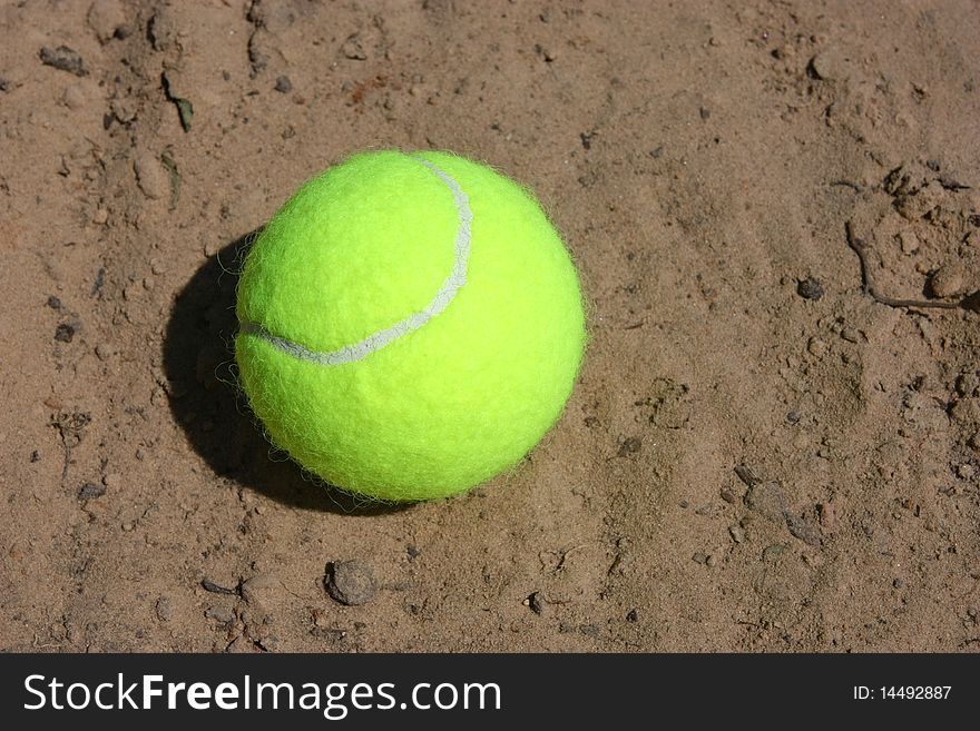 Tennis ball on the gray clay