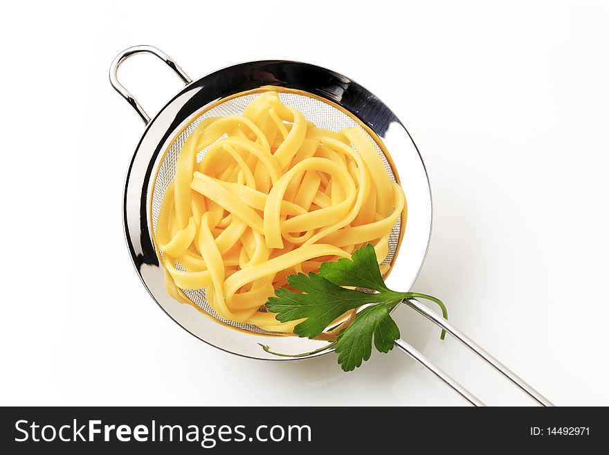 Cooked ribbon pasta in a metal sieve