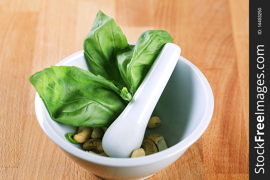 Green basil and cashew nuts in a mortar. Green basil and cashew nuts in a mortar