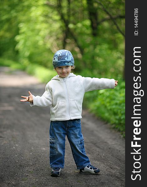 Little boy dressed in blue jeans and white blouse, standing in a forest. Little boy dressed in blue jeans and white blouse, standing in a forest.