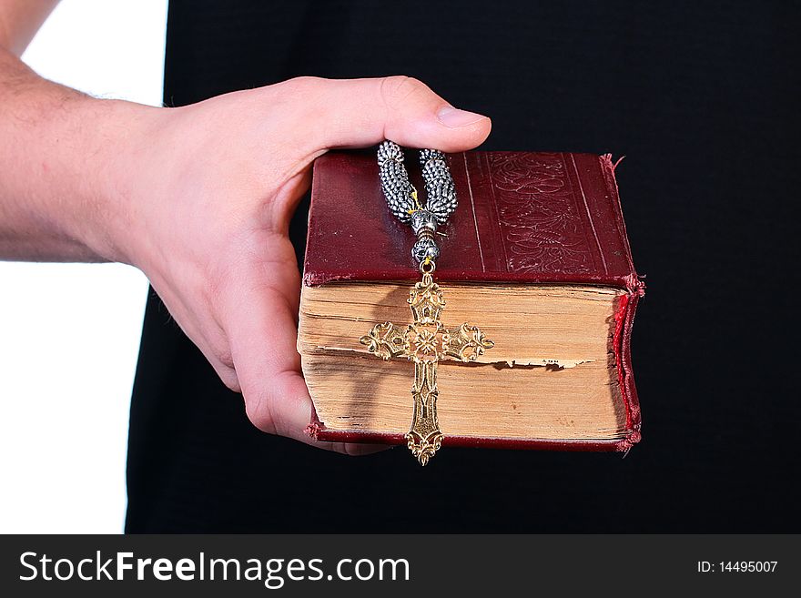 The man's hand holds the old bible with a cross on a chain. The man's hand holds the old bible with a cross on a chain.