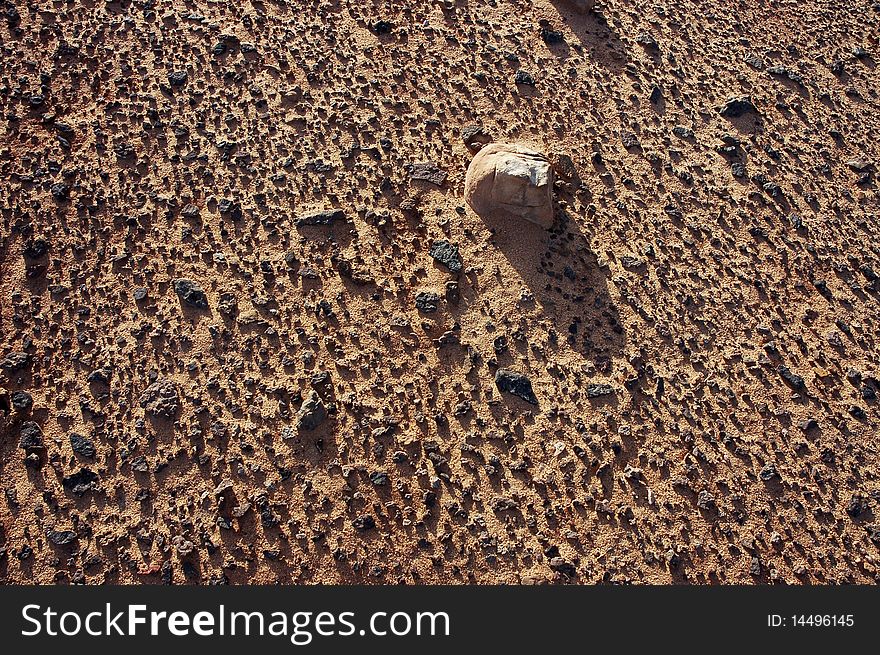 Black volcanic stones on relief desert surface. Black volcanic stones on relief desert surface.