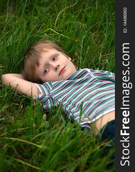 The little boy has laid down on a grass to dream. The little boy has laid down on a grass to dream