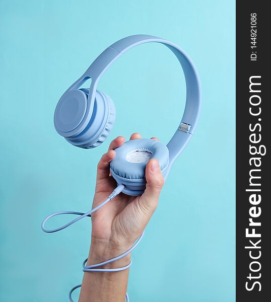 Hand wrapped cable holds headphones on blue background