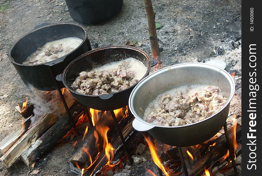 Three cauldrons of meat boiling on a bonfire. Three cauldrons of meat boiling on a bonfire