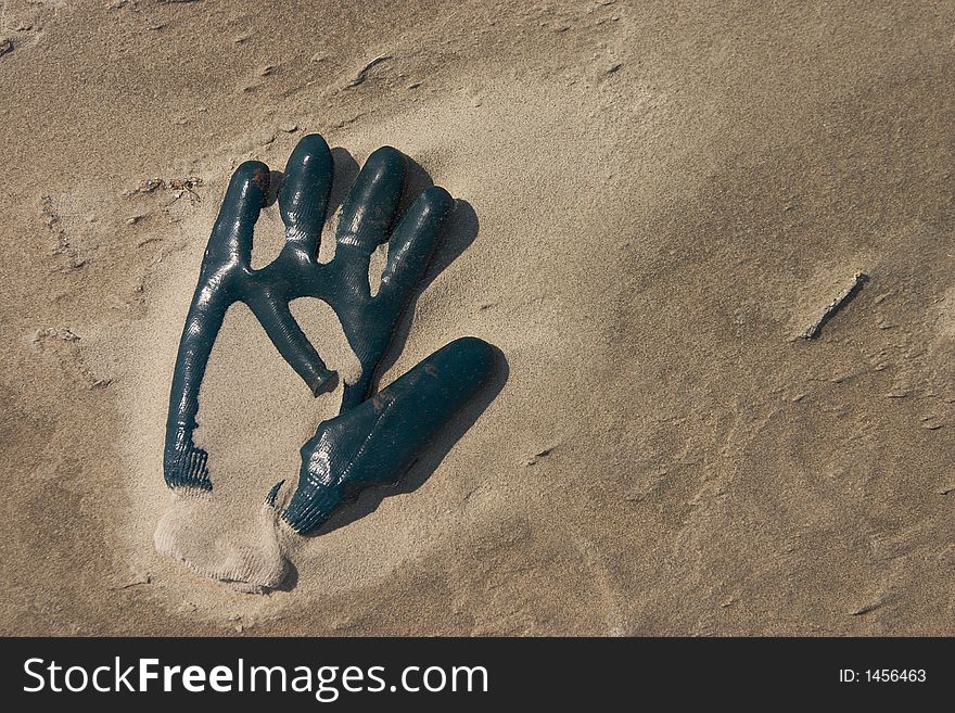 A glove left on the beach overblown with sand