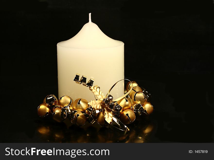 White Christmas church candle with gold bell base on black background. White Christmas church candle with gold bell base on black background.