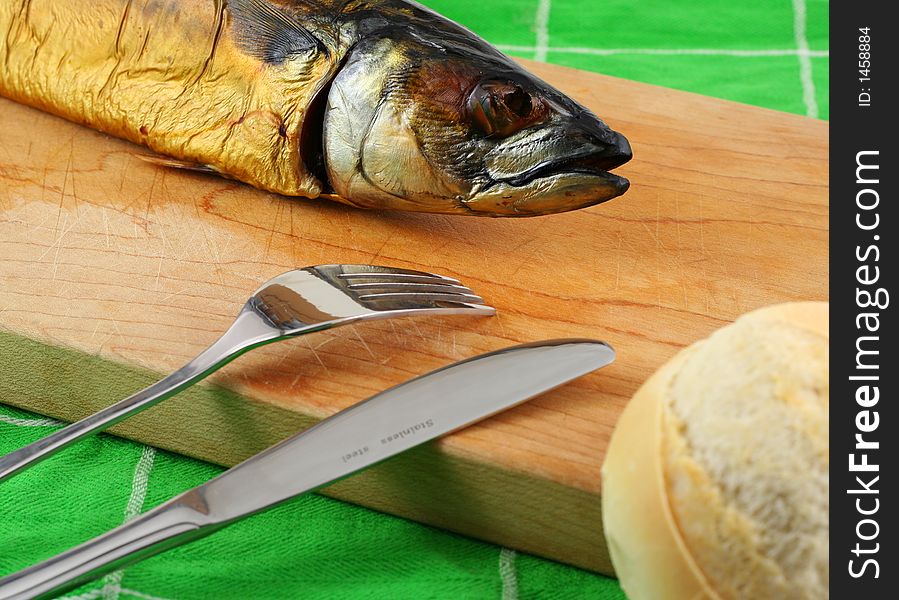 Smoked fish on a cutting board with bread and cuttlery. Smoked fish on a cutting board with bread and cuttlery