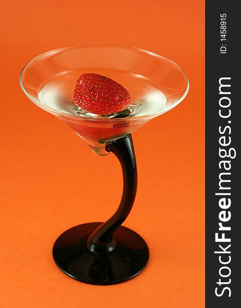 Strawberry in cold water, elegant gin glass on orange background. Strawberry in cold water, elegant gin glass on orange background
