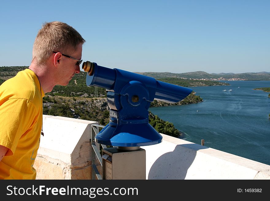 Tourist at a viewpoint looking through a telescope