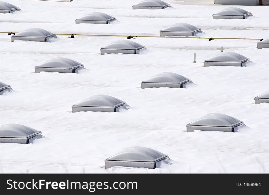 Snow covered rooftop with rows of multiple domed skylights. Snow covered rooftop with rows of multiple domed skylights